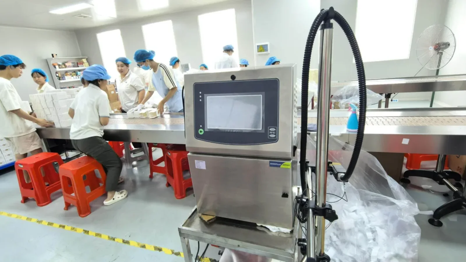 Técnico de fábrica inspeccionando frascos de perfume terminados, relacionado con la consistencia entre lotes de perfume